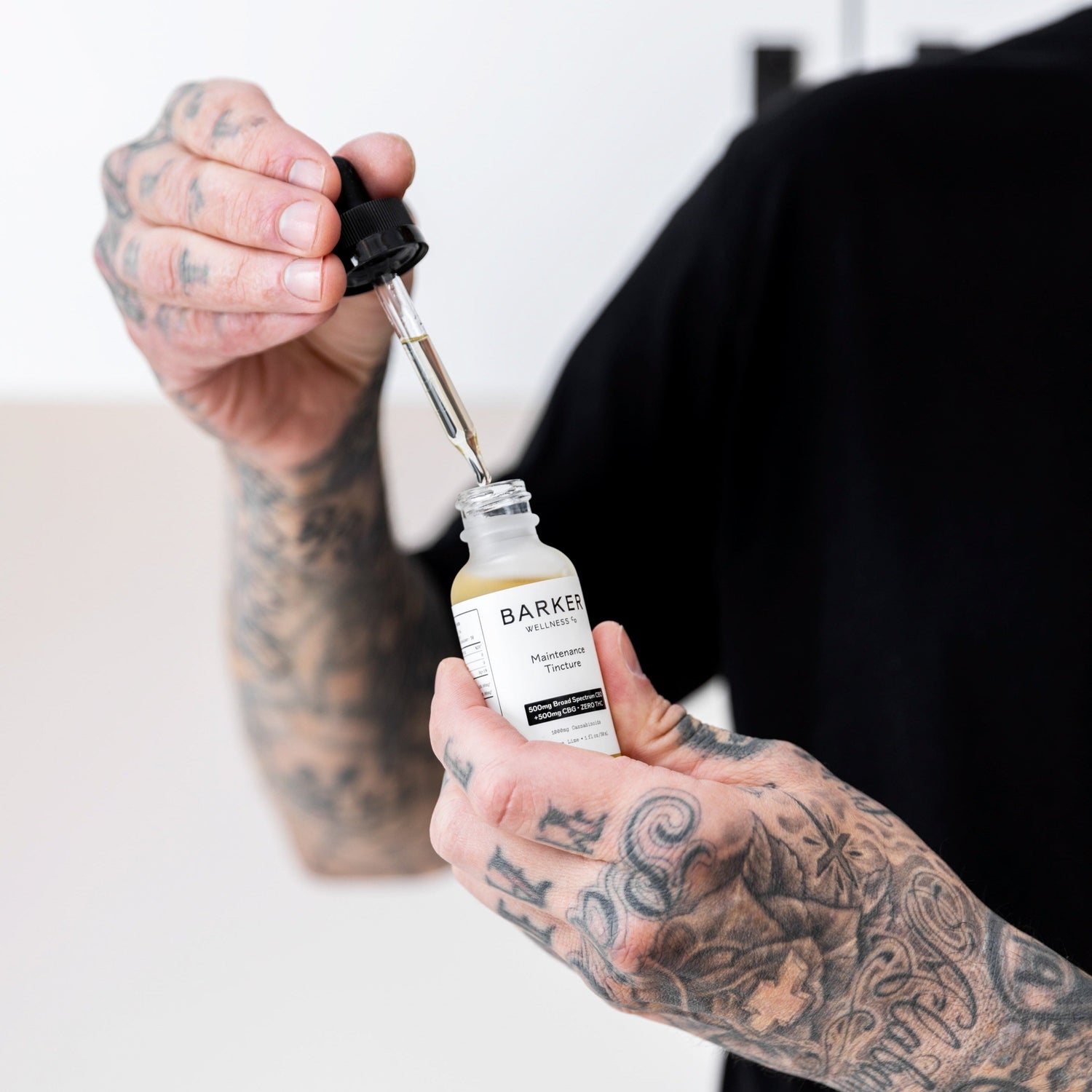 Travis Barker holding Maintenance Tincture Bottle